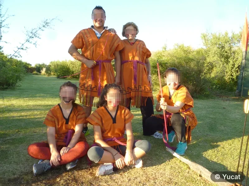 Grupo de cinco adultos vestidos con ponchos comechingones, posando al aire libre.