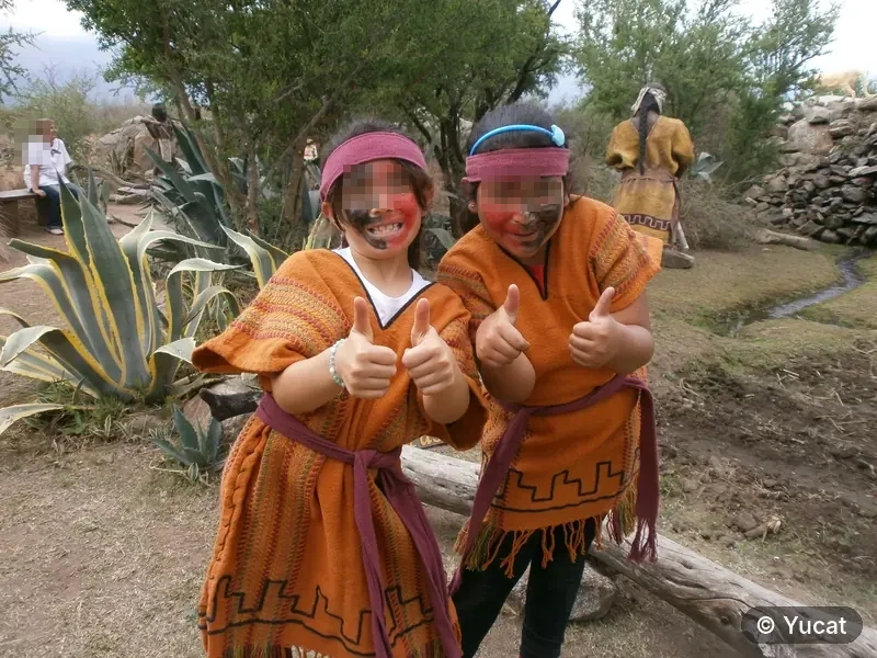 Dos chicas vestidas como comechingonas, con la cara pintada, haciendo el gesto de pulgares arriba.