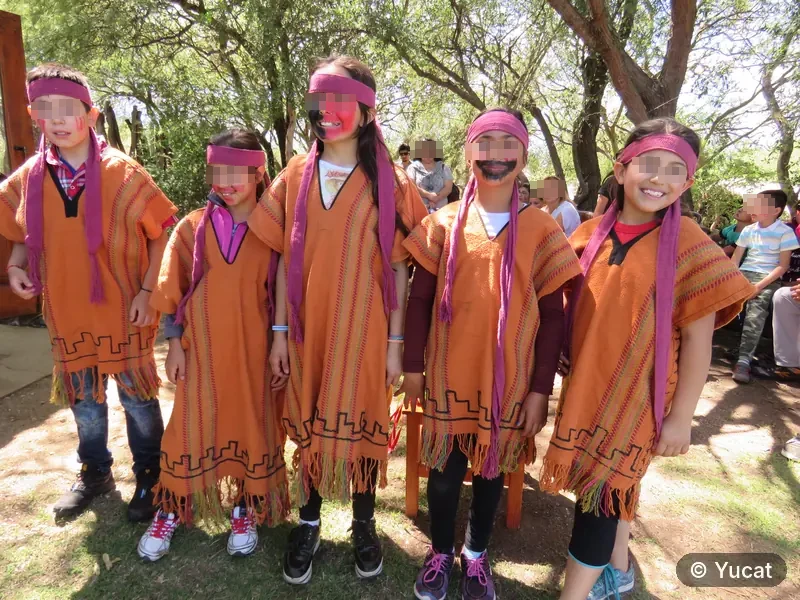 Cinco chicos vestidos con ponchos comechingones y pintura facial, posando para una danza ritual.