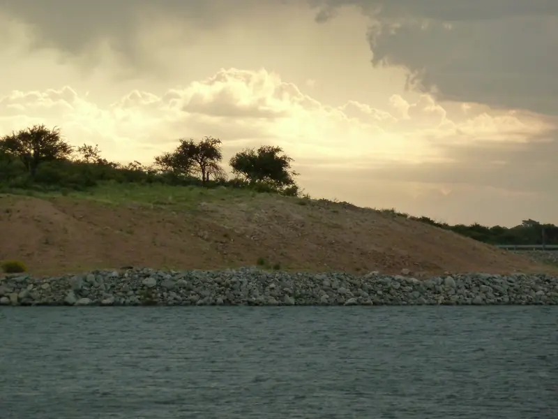 El dique de Villa Larca al atardecer, con su costa de piedras y monte serrano de fondo.