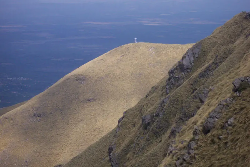 Foto: Merlo San Luis (Wikimedia Commons, CC0 1.0) La cumbre del cerro Mogote Bayo, con su cruz, sobre laderas de pastizal de las Sierras de los Comechingones.