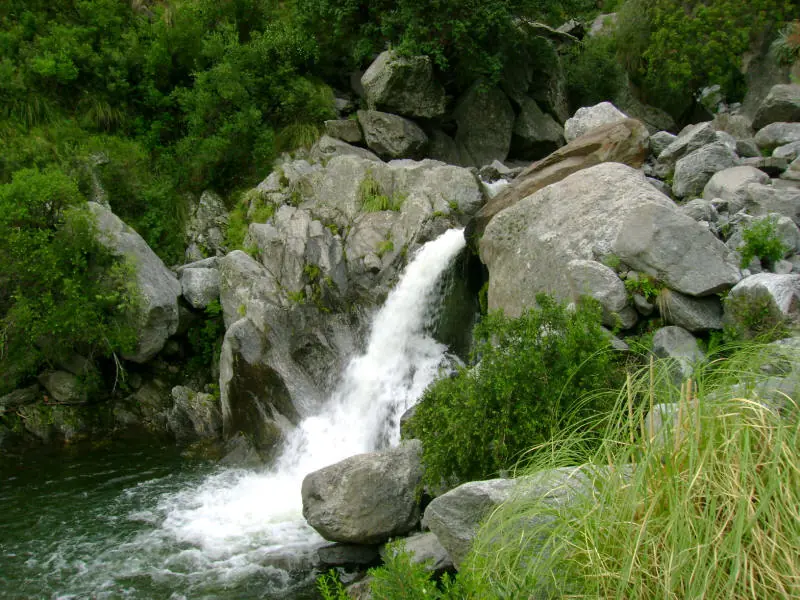 Foto: Merlo San Luis (Wikimedia Commons, CC0 1.0) Un salto de agua del arroyo Pasos Malos que baja entre grandes rocas y monte verde.
