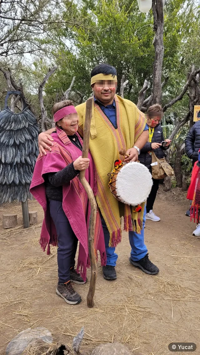 Una pareja de jubilados con ponchos y la cara pintada, posando con un tambor ritual.
